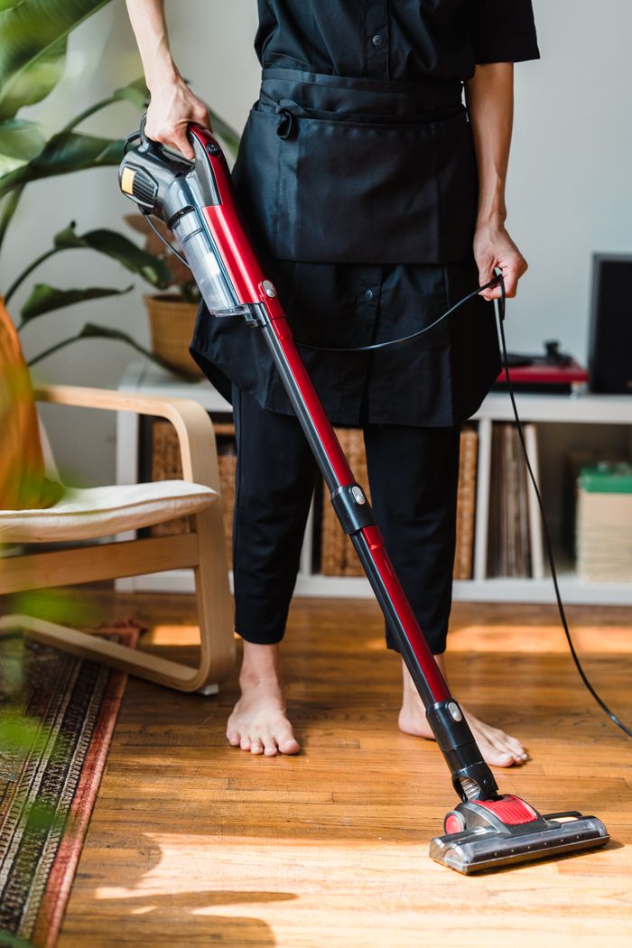 A person vacuuming a wooden floor in a cozy living room setting indoors